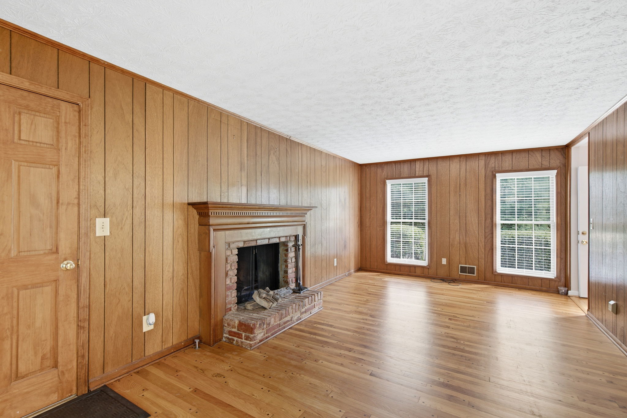 wood paneled family room with brick fireplace at East Cobb home for sale